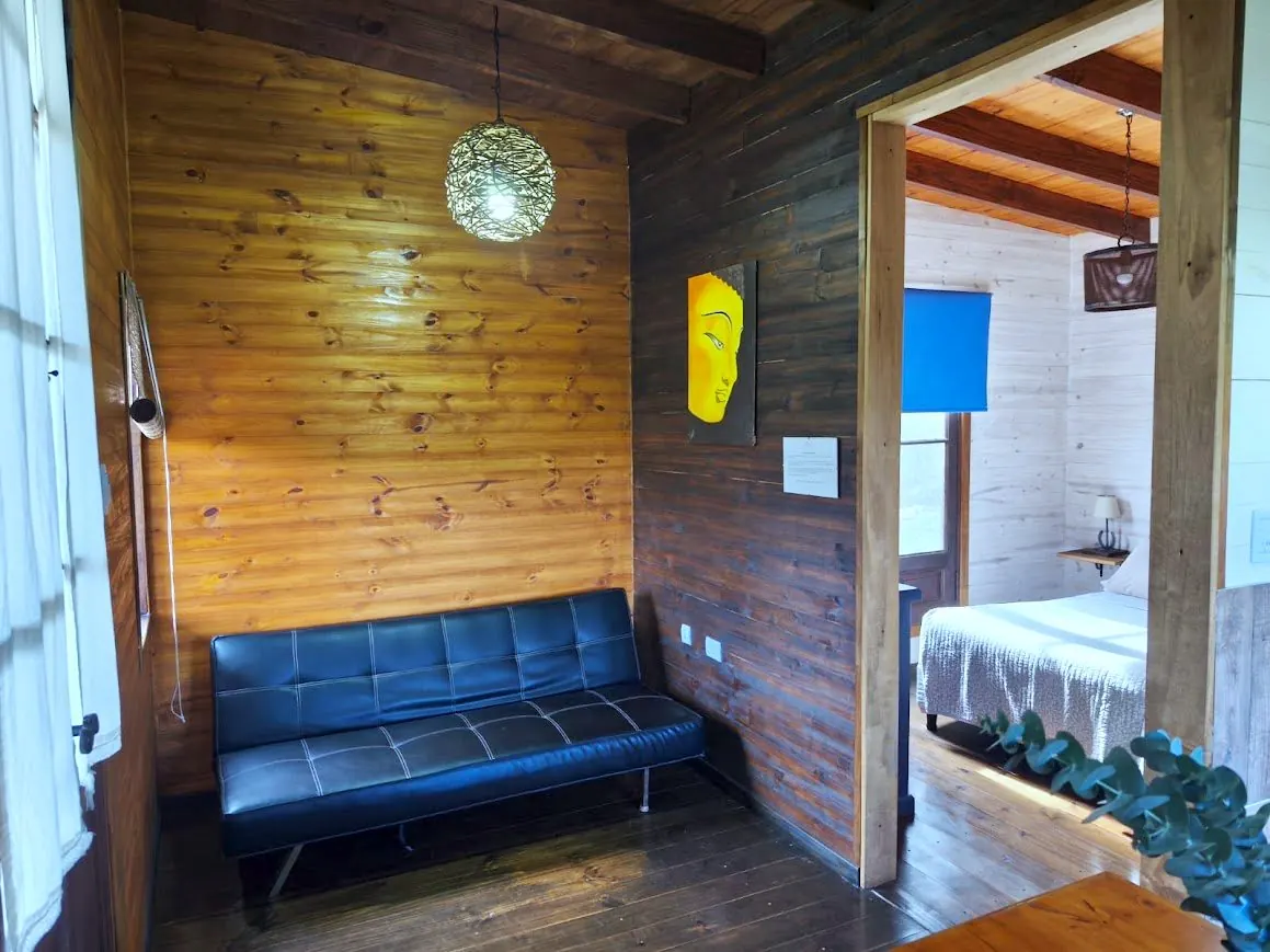 Living de la Cabaña Chuña 1 con sofá cama y paredes de madera