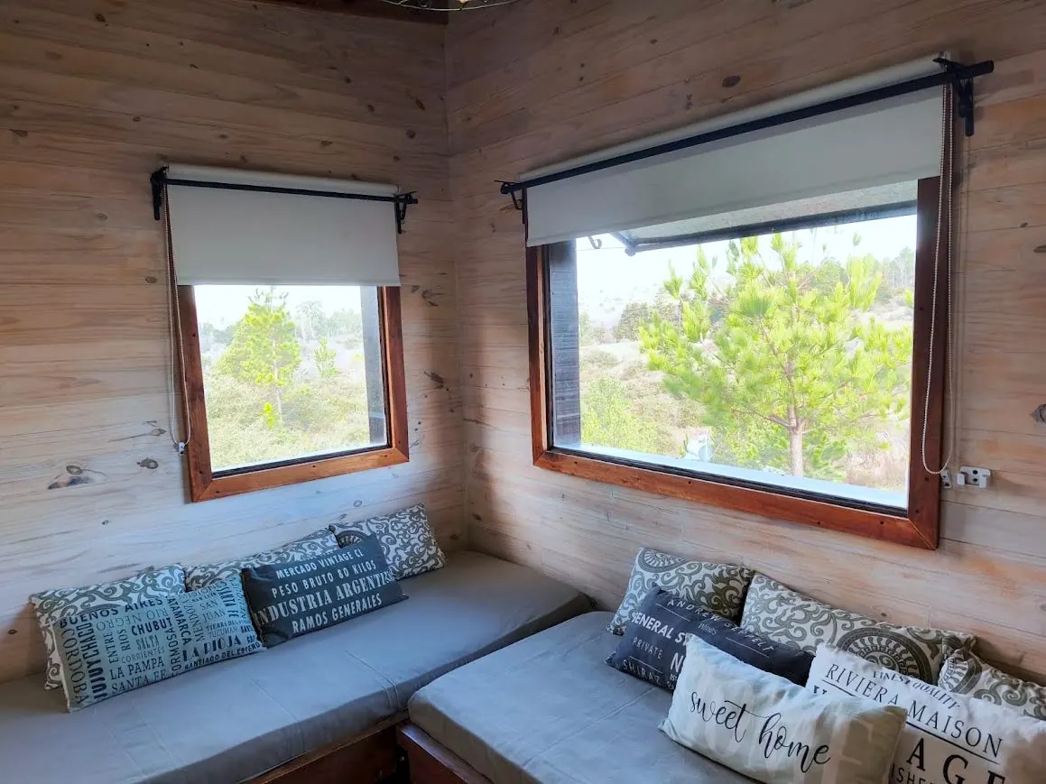 Estar de la Cabaña Chuña 2 con dos sofás cama y ventanales al monte