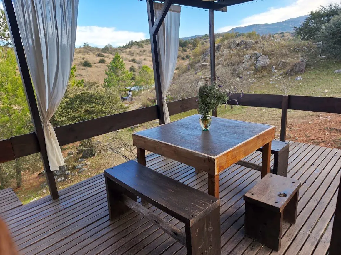 Galería con mesa y bancos de madera y vista panorámica a las sierras de Córdoba