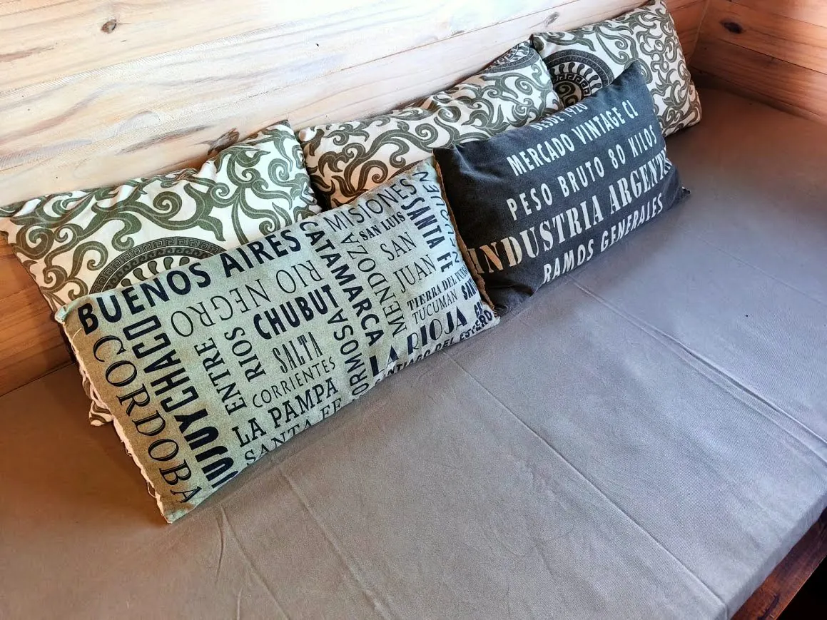 Almohadones estampados con nombres de provincias argentinas en el living de la cabaña