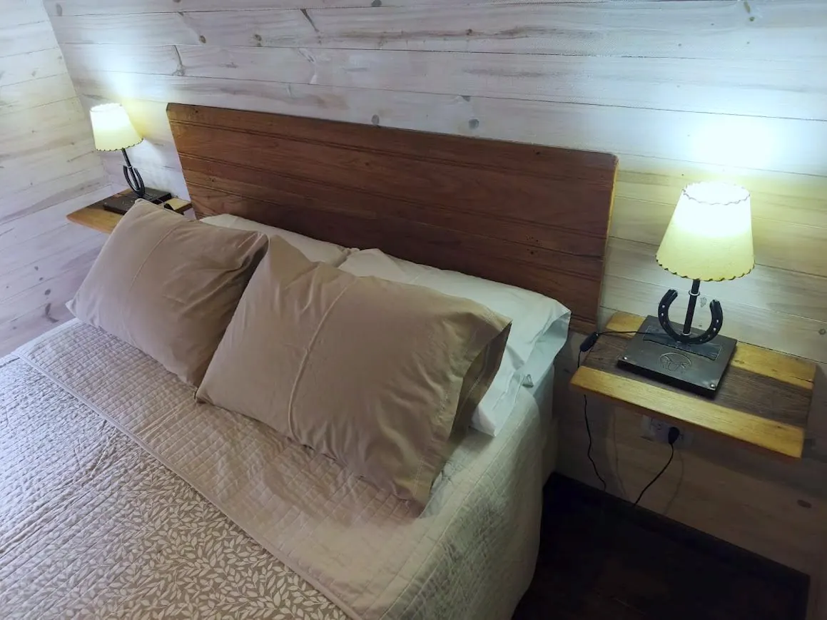 Dormitorio de la cabaña con cabecera de madera y mesas de luz artesanales en Las Chuñas